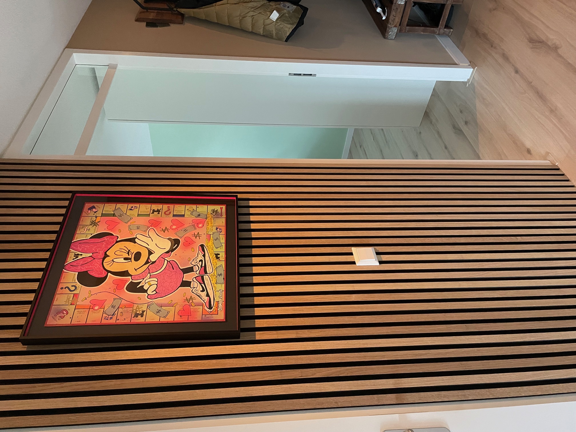 Ingelijst kunstwerk netjes uitgelijnd op een houten lattenwand in een woning in Hoofddorp